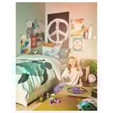 Child draws on bed with ocean-themed decor and colorful supplies.