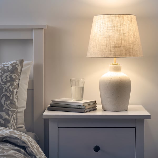 Bedside lamp with ceramic base, brass, & beige shade.