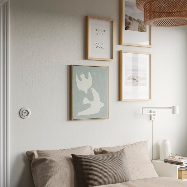 Cozy bedroom with BLODFLÄDER picture frame above bed, adding elegance.
