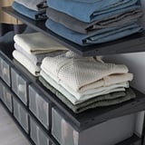 Neatly organized closet with BOAXEL shelves. Jeans, sweaters, and drawers.