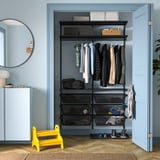 Yellow stool, black BOAXEL closet, neat clothes, blue walls.