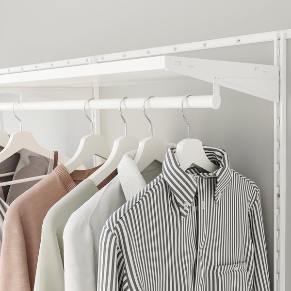 Closet with clothes hangers, striped shirt, beige sweaters, white hangers, white shelves, and hanging rod.