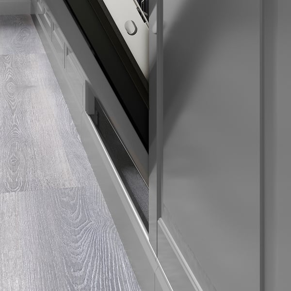 Open grey kitchen cabinets reveal wooden floor with screws.