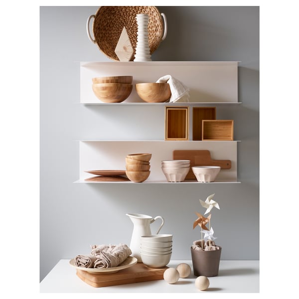 Modern kitchen display with white shelves, wooden bowls, and containers, featuring minimalist design.