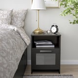 Black BRIMNES bedside table with drawer, books, and lamp