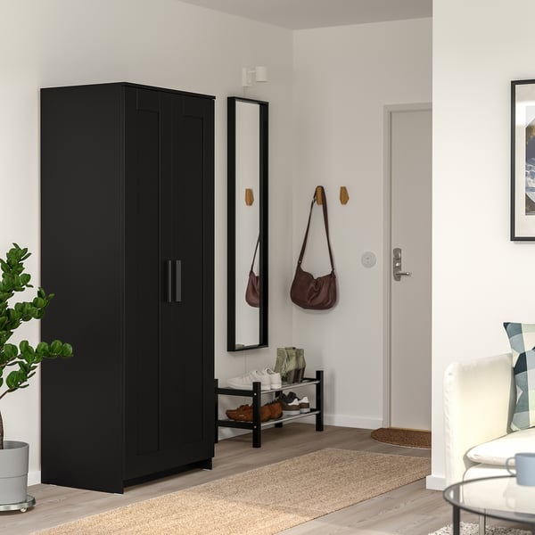 Minimalist entryway with tall BRIMNES wardrobe, mirror, beige rug, and white chair.