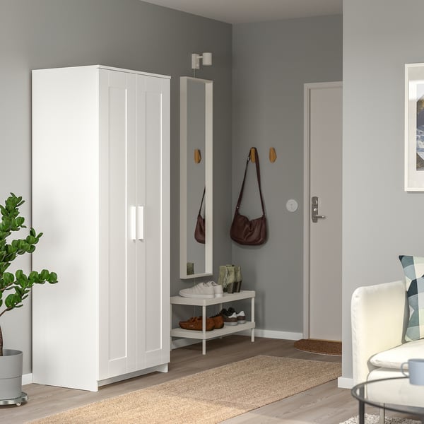 White wardrobe stand beside door, tall for long garments, mirrored, modern.