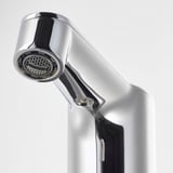 Modern, chrome-plated faucet with a sleek, curved design and an aerator featuring a honeycomb pattern at the nozzle.