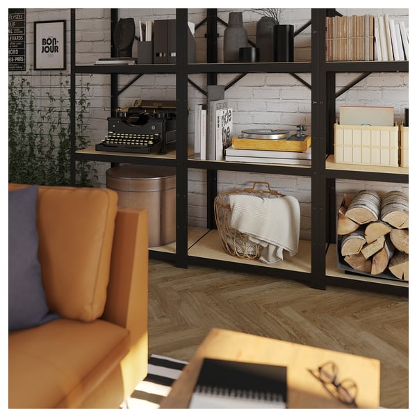 Black metal and wood shelving unit with books, records, and vintage items, against a brick wall.
