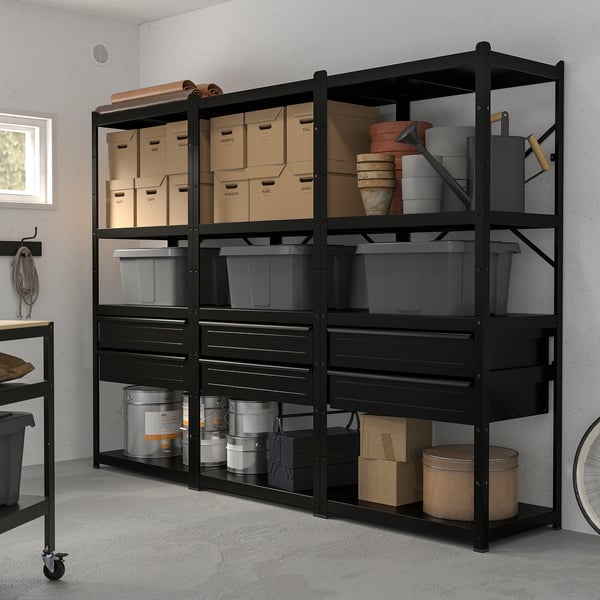 Black metal BROR shelving unit holds multiple boxes and storage bins, robust and versatile, suits various rooms.