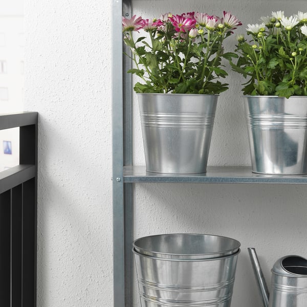 Metal shelf with three potted plants. Flowers in silver planters, adding decorative greenery and color to indoor space.
