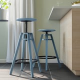 Two blue DALFRED stools under counter, adjustable, wood panelling, white curtains.