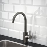 Modern kitchen faucet with high arch, pewter finish, set against white tiled backsplash.