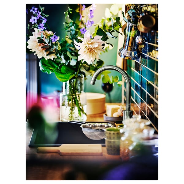 A modern kitchen sink with a delsjon mixer tap in a pewter finish, featuring a bouquet of flowers.