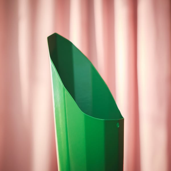 Green powder-coated steel soil scoop, angled for easy grip and precise soil distribution, shown against pink backdrop.