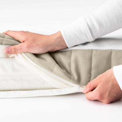 A person is closing a zipper on a childrens mattress. The zipper is hidden in a small pocket for safety.