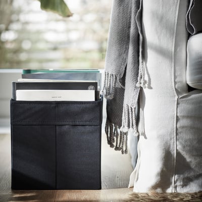 Black fabric storage box, square-shaped with handles, fits bookcases or closets.