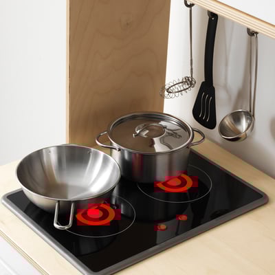 Play kitchen with stovetop, pots, bowl, glowing burners, wall utensils.