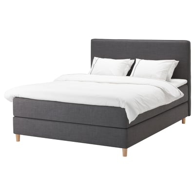 DUNVIK bed: dark grey, upholstered with wood legs, rectangular shape, soft headboard, white linens.