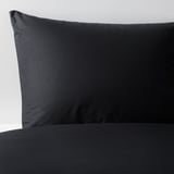 Smooth, black cotton pillowcase on white background, showcasing soft, high-quality fabric.