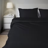 Modern bedroom with DVALA dark grey bedding set on a twin bed, featuring a sleek design and a single nightstand with a lamp.