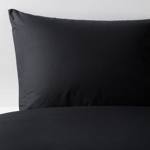 Black pillowcase on a bed, made of soft, natural cotton.