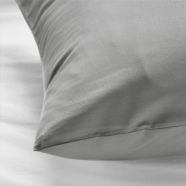 Close-up of soft, grey cotton pillowcase on a white bed, showcasing its smooth texture and quality.