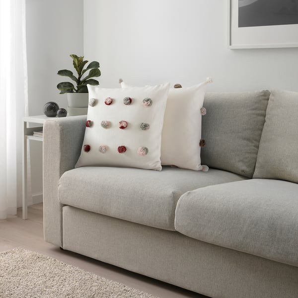 Modern living room with grey sofa, colorful cushion, and plant.