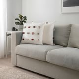 Modern living room with grey sofa, colorful cushion, and plant.