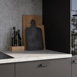 Modern kitchen counter with grey EKBACKEN stone effect laminate, wooden cutting boards, and oil bottles.
