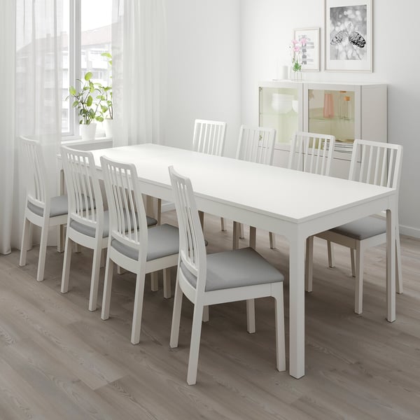 White extendable dining table with 6 gray cushion chairs in modern room.
