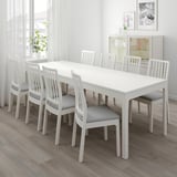 White extendable dining table with 6 gray cushion chairs in modern room.