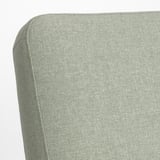 Soft, curved green cushioned chair corner, showcasing quality upholstery and stitching.