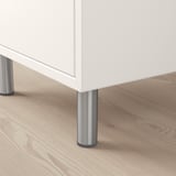 White cabinet with stainless steel legs on wooden floor.