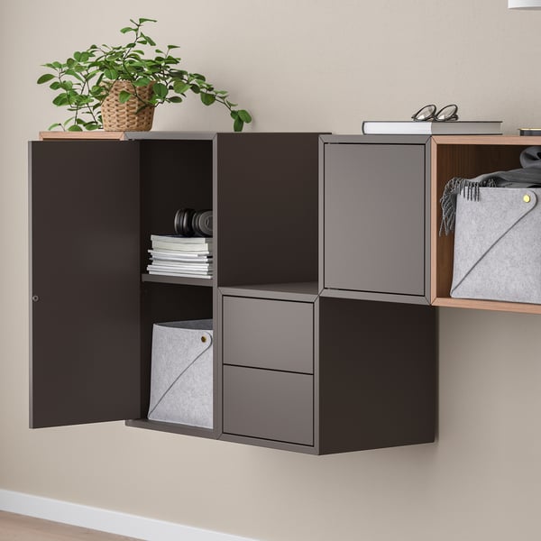 Wall-mounted shelf unit with open and closed storage compartments, holding books, plant, and organisers.