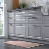 Small, handwoven kitchen rug in soft colors, made from repurposed cotton, providing comfort and reducing slips.