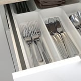 A silverware organizer with forks, knives, and spoons in compartments, making kitchen utensils easy to access and store.
