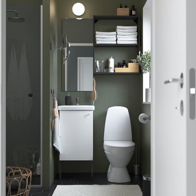 Small, modern bathroom with a white ENHET vanity, round mirror, and toilet. Dark green walls, black floor. Testing.