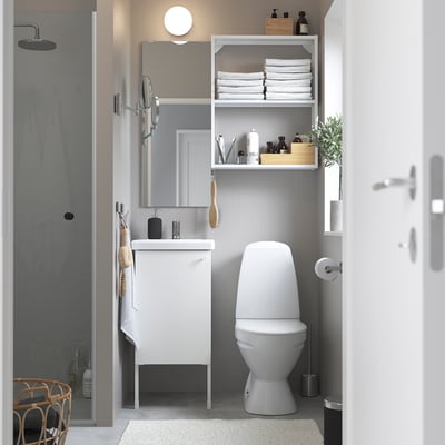 Minimalist bathroom with small sink, overhead shelves, wall-mounted toilet.