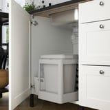 Modern kitchen cabinet with integrated sink and waste sorting, white framed door, designed for clean organization.