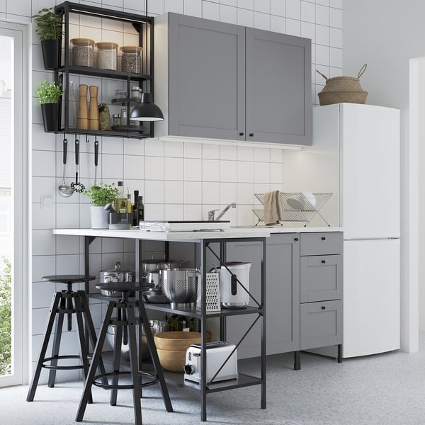 Modern kitchen with ENHET series: grey cabinets, black metal stools, white countertop, stainless steel appliances, hanging shelves, tiled backsplash.