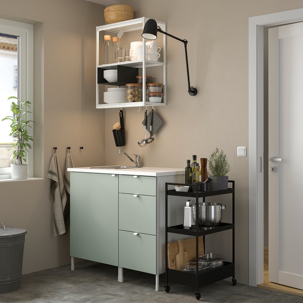 Green ENHET kitchen unit with sink, shelves, drawers, and adjustable light. Compact and efficient storage.