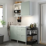 ENHET kitchen: green base cabinet with drawers, wall & open storage, single-bowl sink, rolling cart with items.