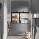 ENHET bathroom storage unit with cabinets, towels, and toiletries. Wicker basket in front, glass doors in center.