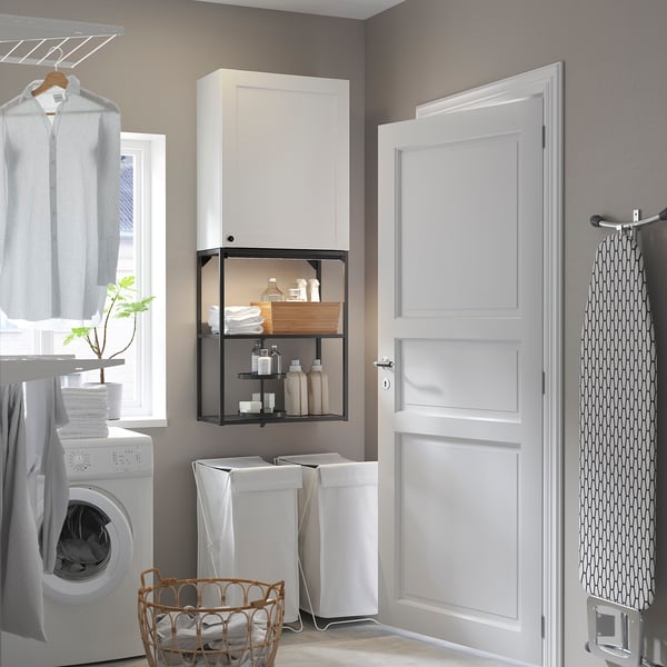 Modern laundry setup: ENHET white cabinet stores laundry items & machine. Glass fronted shelf, grey door.