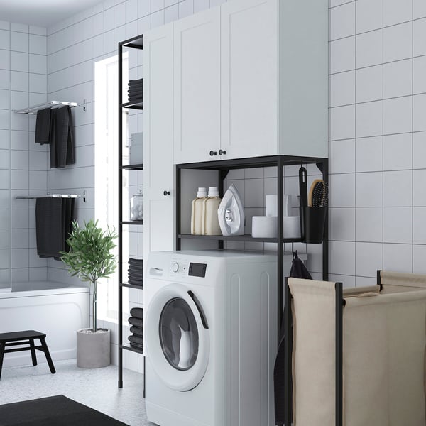 White ENHET laundry unit in bathroom corner with washing machine, cabinets, shelves, and towels.