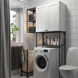 White ENHET laundry cabinet and shelves for washing machine, iron, detergents, and towels.