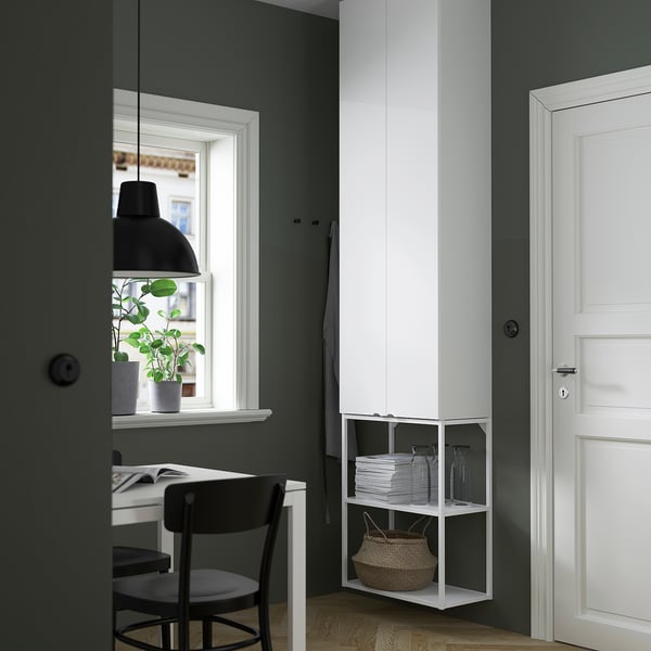 Modern office with ENHET white shelves and desk, black chair, plant by window.