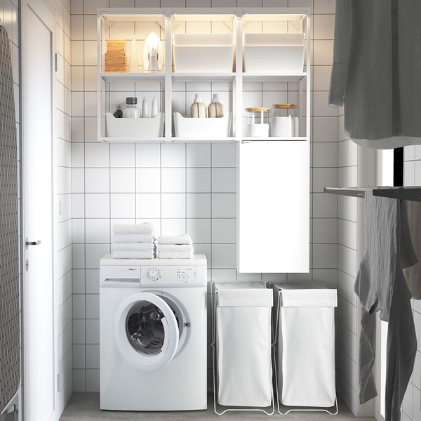 Modern minimalist laundry room with white ENHET storage, washing machine, towels, and baskets. Clean, organized with glossy surfaces.
