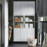 White ENHET storage unit with shelves and wooden basket holding towels. Modern kitchen or bath design with minimalist style.